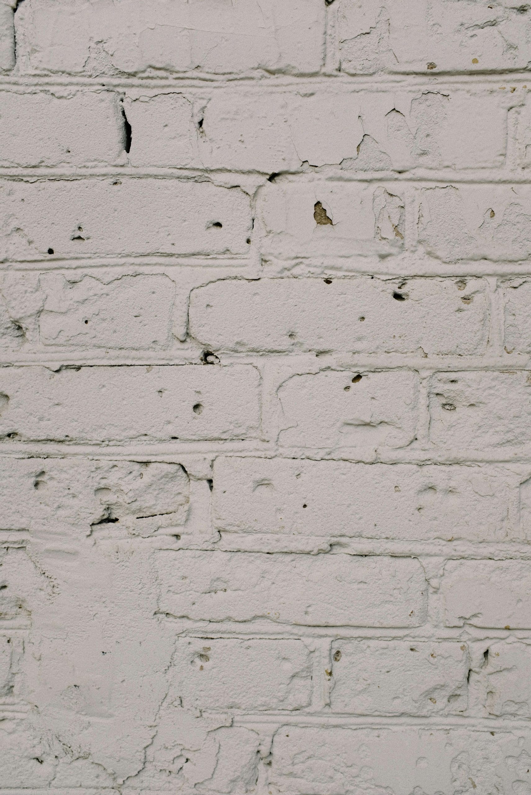 Home Close-up of a rustic white painted brick wall texture with weathered details.